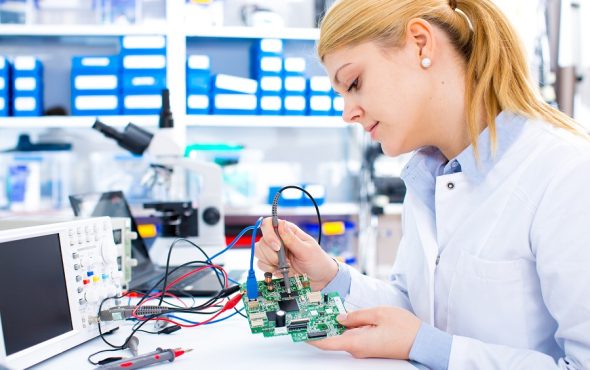 Engineer working with circuits. A woman engineer solders circuit